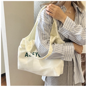 Détail du sac fourre-tout en toile blanche avec lettrage AREYO vert et bandoulière