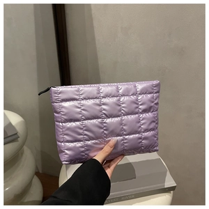 Close-up of quilted lavender cosmetic bag featuring smooth glossy texture and black zipper