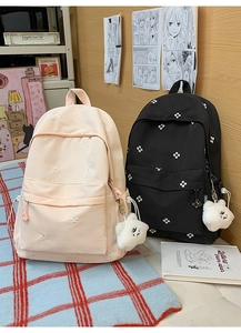 Detail view of school backpacks with floral embroidery and cute plush bear charms