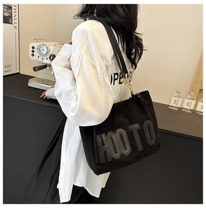Détail du sac cabas noir avec écusson HOOTO et bandoulière en chaîne et cuir
