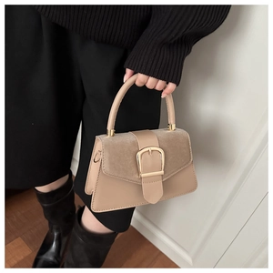 Close-up of beige patchwork handbag with textured flap and elegant gold D-ring buckle
