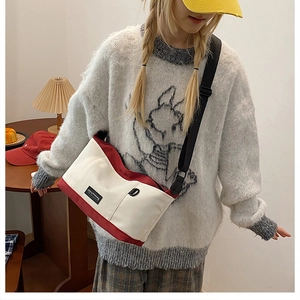 Detailed view of bicolor canvas crossbody bag with red trim and adjustable shoulder strap