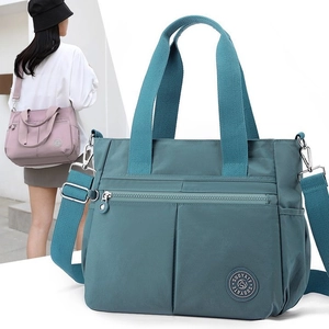 Large blue nylon tote bag with multi-pockets and adjustable strap shown on model