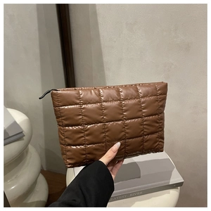 Close-up of brown quilted leather makeup bag with grid stitching and black zipper