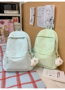 Detail of floral embroidery on light blue and green student backpacks with cloud pendant