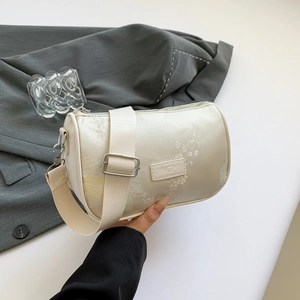 Elegant off-white cylindrical crossbody bag with floral embroidery and wide strap