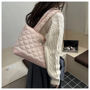 Close-up of pink quilted tote bag featuring a delicate metal bow charm detail