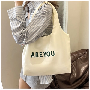 Photo de style d'un grand sac cabas crème avec inscription AREYOU verte portée