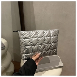 Close-up of a silver quilted makeup bag with metallic finish and black zipper closure