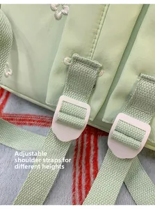 Detail of adjustable green shoulder strap with white floral embroidery on backpack