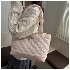 Detail view of pink quilted tote bag with silver bow ornament and padded shoulder strap