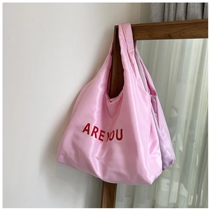 Détail d'un cabas en satin rose avec lettrage rouge ARE YOU sur une surface soyeuse
