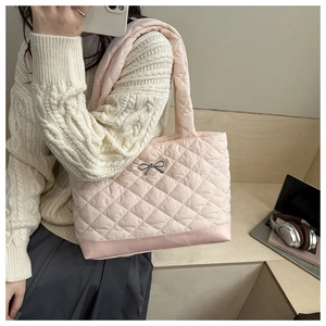 Detail of light pink quilted tote bag with silver metal bow and reinforced leather base