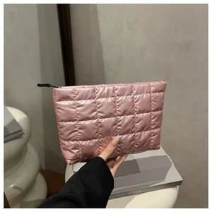 Detail of pink quilted makeup bag with glossy nylon texture and black zipper closure
