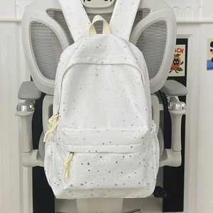 Vue détaillée du sac à dos blanc à motifs étoiles argentées avec tirettes de nœuds jaunes