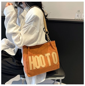 Détail du sac cabas en daim orange avec lettrage HOOTO et anses en métal doré chic