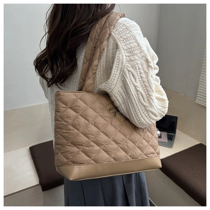 Detailed back view of a brown quilted tote bag with bow detail on a fashion model