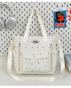 Dettaglio della borsa tote bianca a stelle con tasca frontale e logo DALAIBIN
