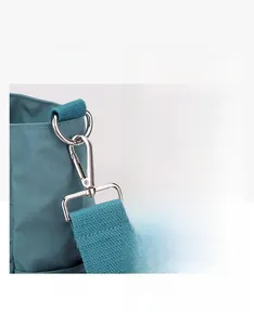 Detail view of sturdy metal hooks and smooth zippers on the blue nylon shoulder bag