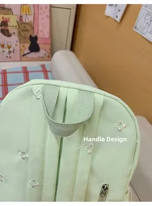 Close-up of the woven handle and floral embroidery on a light green school backpack