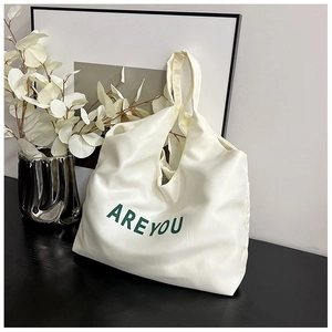 Détail du cabas en cuir PU blanc avec inscription AREYOU imprimée en vert foncé