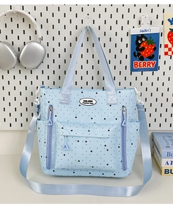 Dettaglio della borsa tote in tela azzurra con motivo a stelle e design multitasche