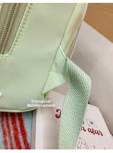 Detail of reinforced triangle stitching on the light green student backpack strap