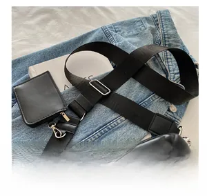 Close-up of a black quilted crossbody bag with wide nylon strap and mini pouch