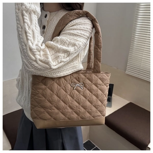 Macro detail of brown quilted tote bag with silver metal bow and nylon diamond pattern