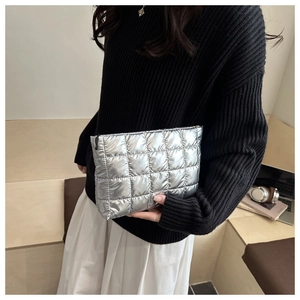 Close-up of silver quilted metallic makeup bag with black zipper in modern cafe setting