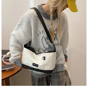 Detail view of small black and white canvas crossbody bag with nylon shoulder strap
