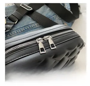 Detail of the dual silver zippers on the black quilted crossbody bag with wide strap