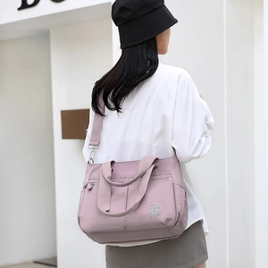 Detail of light purple nylon shoulder bag with adjustable strap in outdoor street setting
