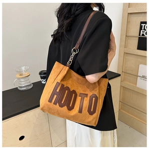 Détail du sac cabas en daim caramel avec lettrage HOOTO et bandoulière dorée