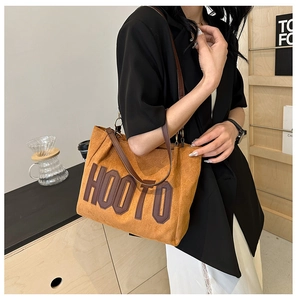 Détail du sac cabas en daim marron avec lettres HOOTO en cuir et bandoulières