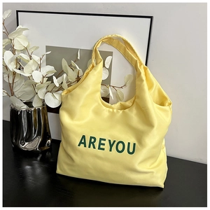 Gros plan sur un sac cabas en satin jaune avec inscription AREYOU verte élégante