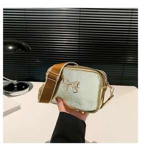 Detailed macro view of the gold metallic textured finish and bow ornament on small square bag