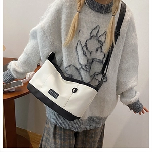Detail view of the black and white canvas crossbody bag with adjustable strap on model