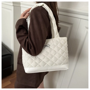 Detail of white quilted tote bag featuring a silver bow buckle and thick padded strap