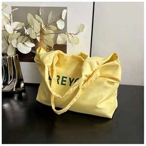 Vue détaillée du sac cabas en tissu jaune avec lettrage Rey vert sur une table noire