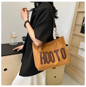 Détail du sac cabas en daim avec patch en cuir HOOTO et bandoulière en chaîne métal