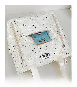 Dettaglio della borsa a tracolla in tela beige con stelle nere e tasca con zip