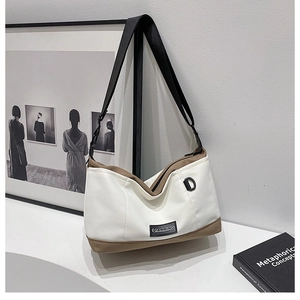 Detail view of canvas crossbody bag with brown leather trim and black nylon shoulder strap