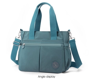 Detail view of teal nylon tote bag with silver zippers and Suoyate brand logo