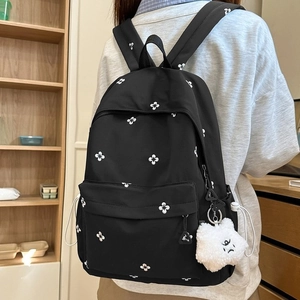 Student backpack with floral pattern and plush cloud pendant in a warm study room setting