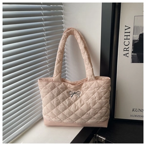 Detail of light pink quilted tote bag showing classic rhombic stitching and silver bow charm