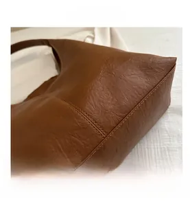 Close-up of litchi texture leather and reinforced corner stitching on dark brown tote bag