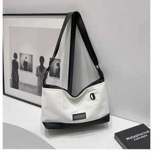Detail of adjustable strap and D-ring on black and white canvas crossbody bag