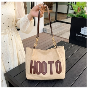 Détail d'un sac cabas kaki avec lettrage HOOTO et bandoulière en chaîne dorée sur mannequin