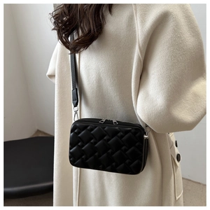 Chic black quilted crossbody bag with wide shoulder strap shown on model's shoulder